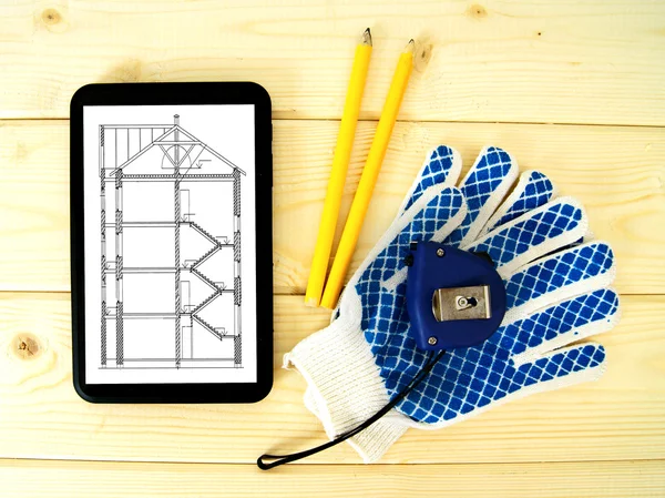 Tablet, drawings and working tools on a wooden background.