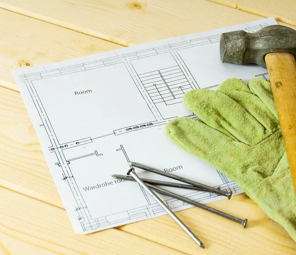 Repair work. Drawings for building, hammer and gloves on wooden background.