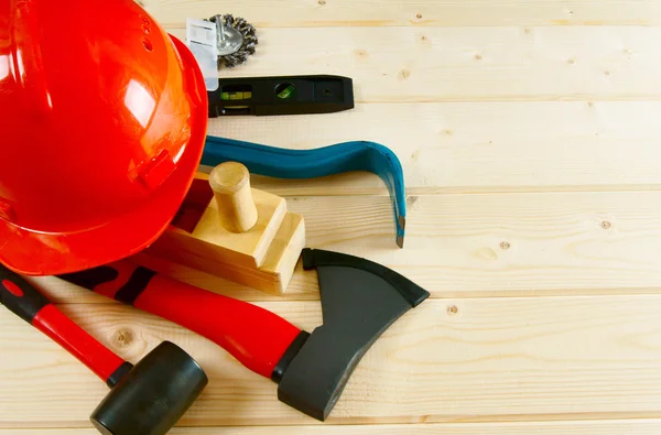 Helmet, mount, axe, plane and other tool on a wooden background.