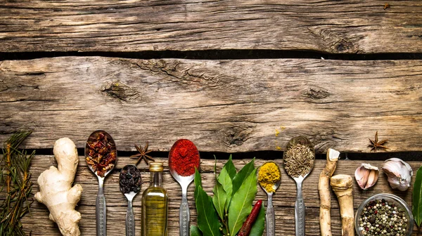 Fragrant spices in spoons with herbs, garlic and olive oil.