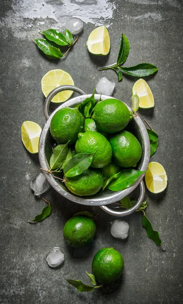 Lime background. Fresh limes in a saucepan with slices and leaves around.