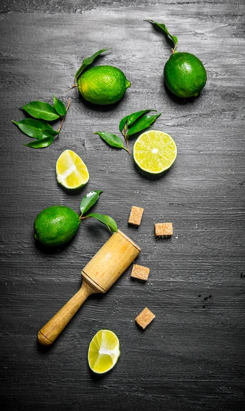 Lime background.Fresh limes with leaves, sugar and pestle .