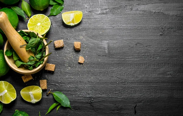 Lime background. The mortar with mint, sugar , lime slices and leaves .