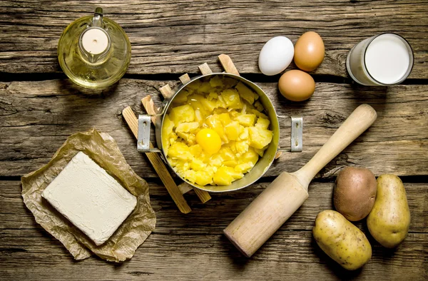 Ingredients for mashed potatoes - eggs, milk, butter and potatoes on wooden background.