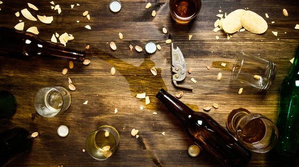 In the process of party - spilled beer, bottle caps and leftover chips on the table.