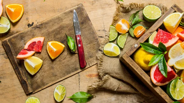 Sliced citrus fruits - grapefruit, orange, tangerine, lemon, lime on the old Board with box.