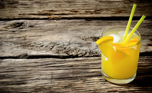 Cocktail of fresh oranges with ice and straw on wooden background . Free space for text.