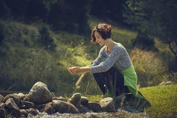 Woman washing hands in mountain stream water