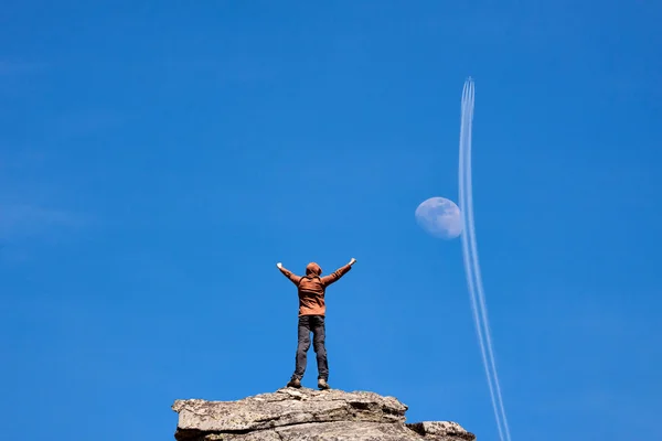 Man standing on the top of the mountain over blue sky with moon