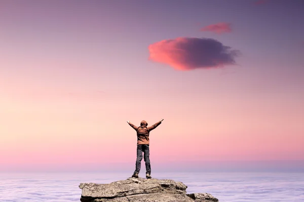 Man standing on the top of the mountain over clouds