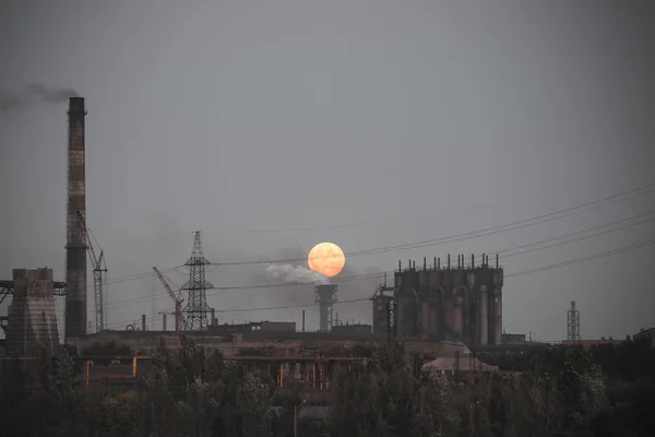 Panorama of full moon rising over industrial landscape