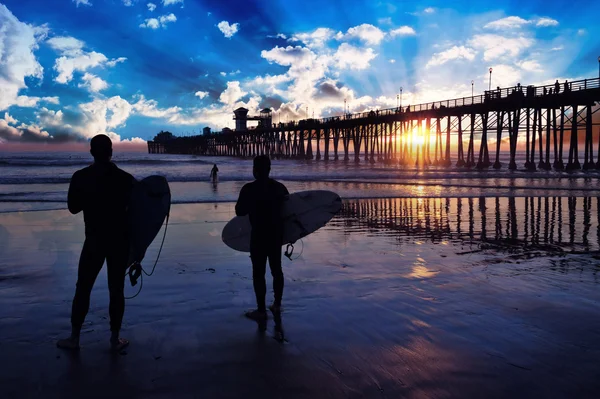 Surfers watch an Oceanside California sunset.