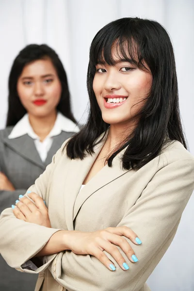 Businesswomen wearing suits standing and folding arms