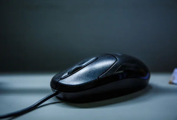 Black computer mouse on a black background.