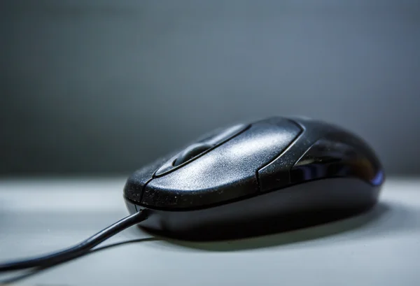 Black computer mouse on a black background.