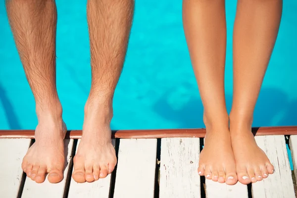 Close-up of beautiful woman and man legs near by swimming pool
