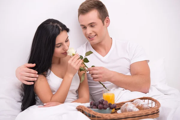 Man giving rose to his wife while having breakfast in bed