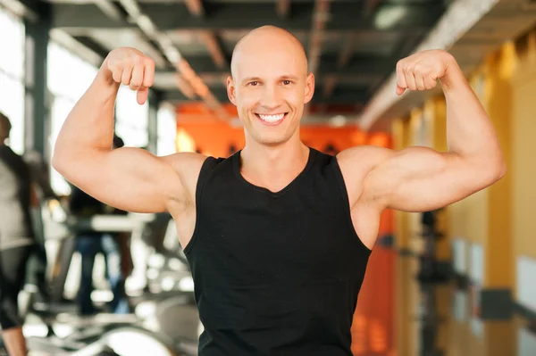 Smiling man standing and showing his muscles