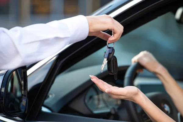 Close up of car dealer giving keys to woman