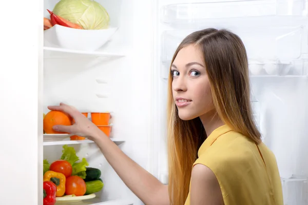 Young beautiful woman picking food from fridge
