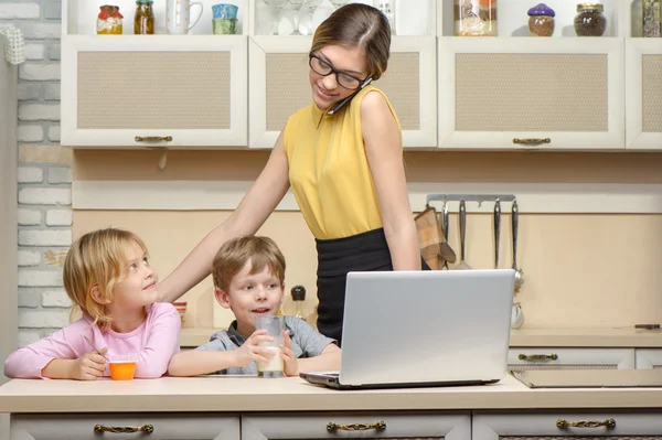 Young business woman in kitchen with her little children