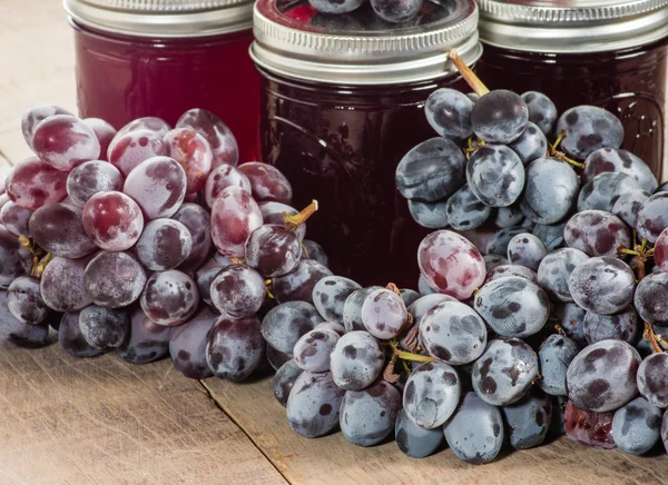 Three jars of grape jelly with grapes