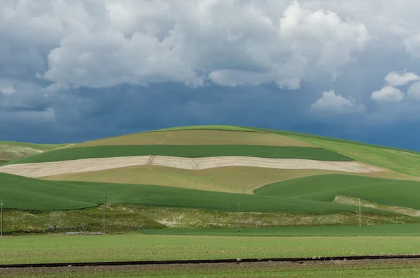 Rolling green farm fields with angry storm