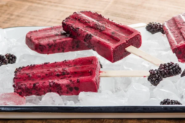 Frozen berry pops on tray of ice