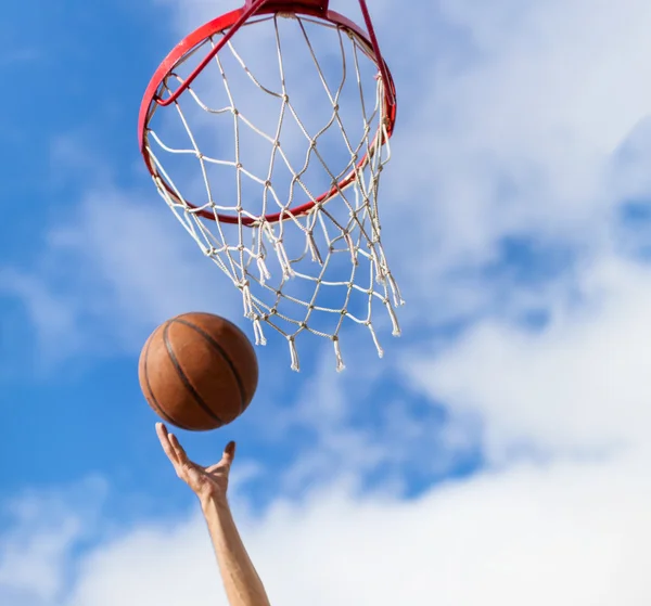 Hands throwing basketball ball into basket