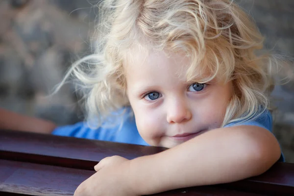 Little child hidden behind a wooden bench
