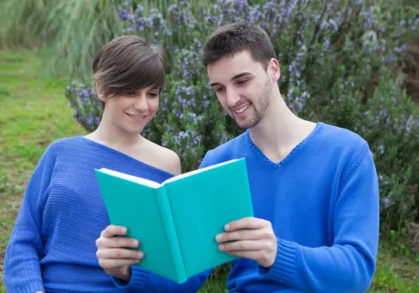 Young couple together reading a book together in the park