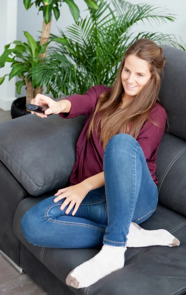 Woman sitting on the sofa with a remote control