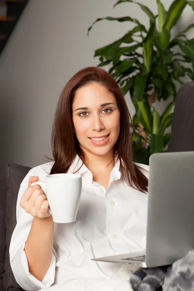 Woman with coffee cup using laptop