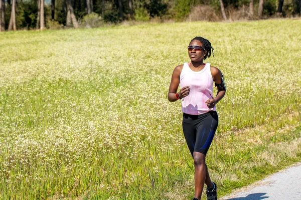 African teen girl jogging next to field.