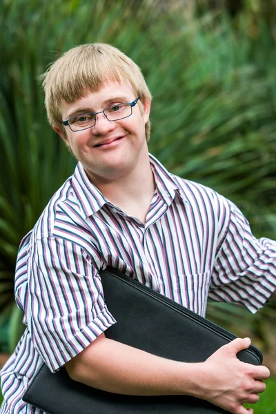 Young student with down syndrome holding files outdoors.