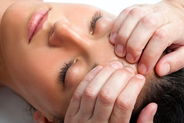 Woman receiving massage on forehead.