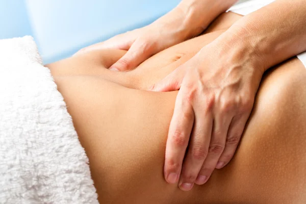 Hands massaging female abdomen