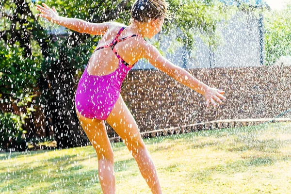 Little girl having fun under water drops.