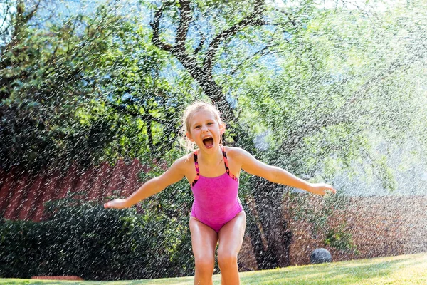 Little girl shouting under water drops.