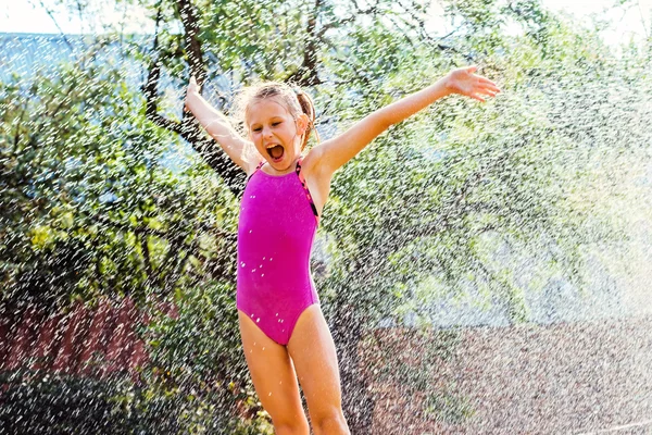 Little girl shouting under water sprayer.
