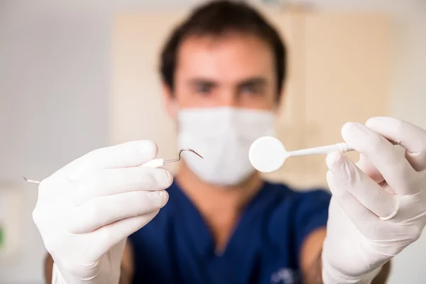 Young dentist showing his medical instruments