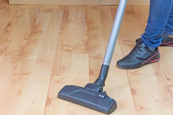 Woman is vacuuming laminate floor
