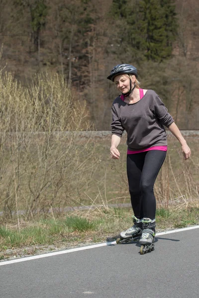 Middle aged woman on inline skates outdoors