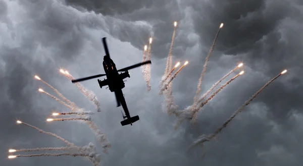 Silhouette of an attack helicopter firing flares