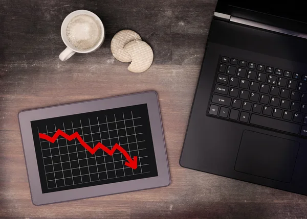 Tablet touch computer gadget on wooden table, graph negative