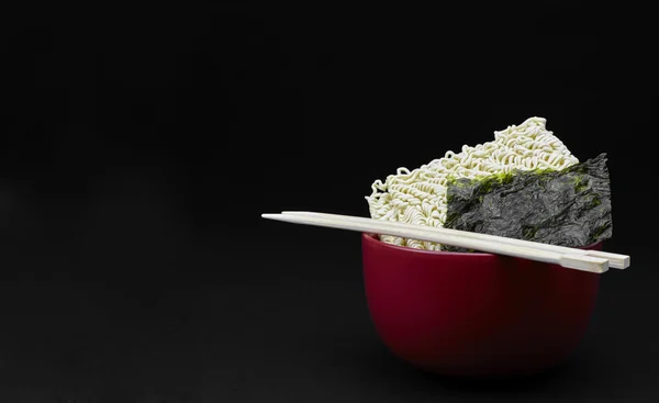 Asian Saimin Noodles and Japanese Nori Seaweed with Chopsticks on Black Background