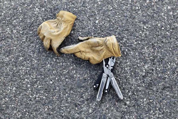 Man\'s Leather Work Gloves with Pliers on Asphalt