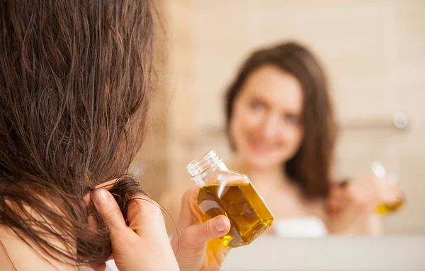 Woman applying oil mask to hair tips
