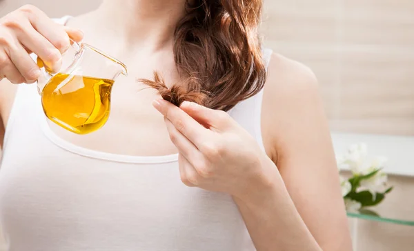 Woman applying oil mask to hair tips