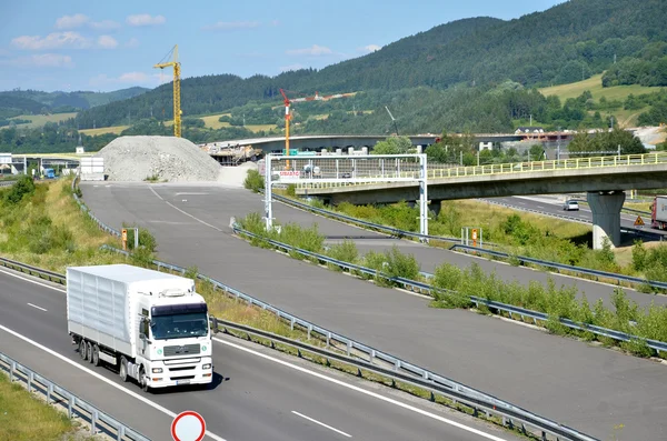 White MAN truck drives on slovak D1 highway. In background is new part of this way under construction.